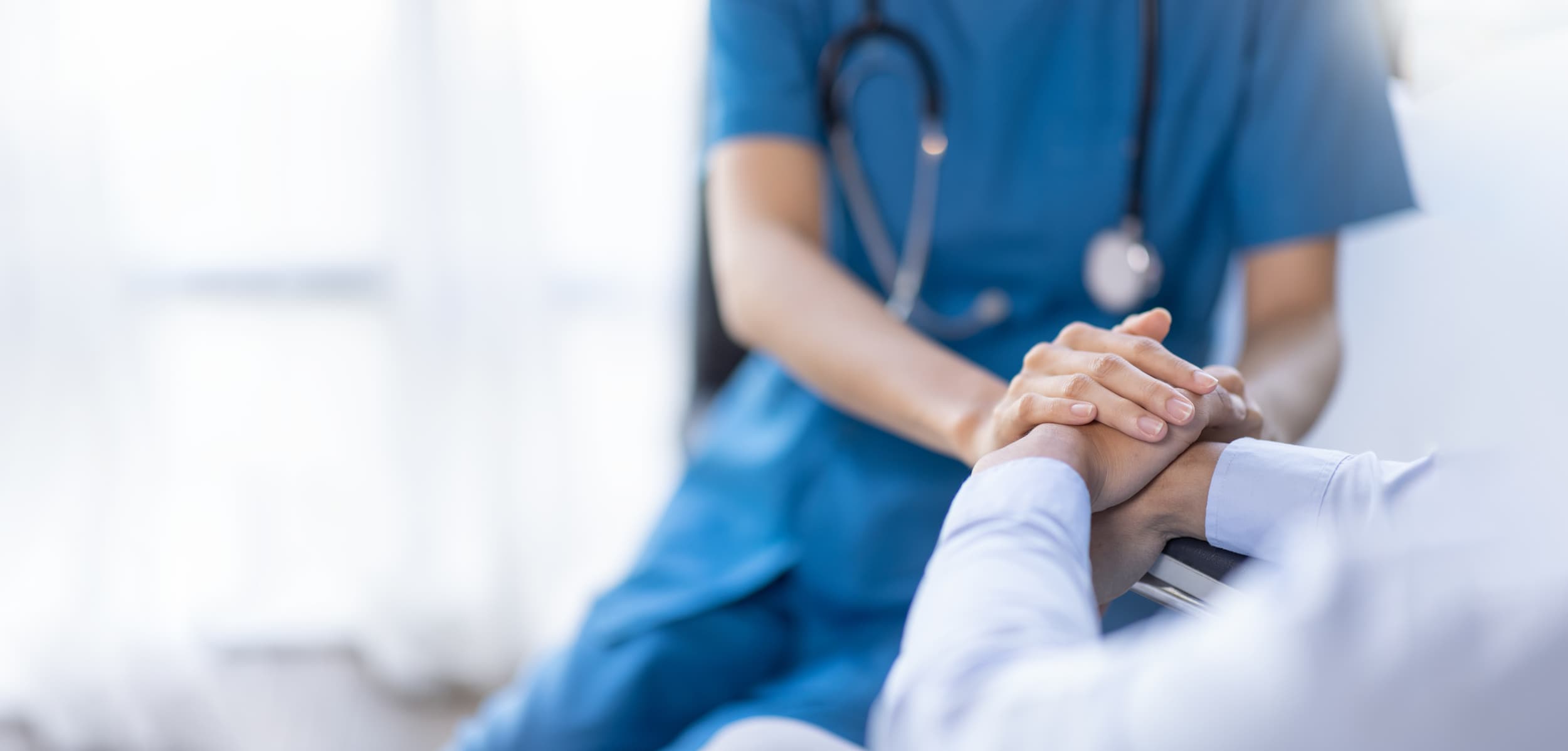 Physician offering supportive care by holding a patient's hand